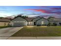 Charming single-story home with well-manicured lawn and two-car garage under sunset at 955 Hunters Meadow Ln, Lakeland, FL 33809