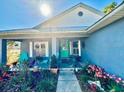 Inviting front porch with beautiful flowers and plants, seating and a bright green door at 811 W Heron Pl, Winter Haven, FL 33884