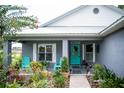 Charming front porch with turquoise chairs and door, surrounded by well-maintained landscaping at 811 W Heron Pl, Winter Haven, FL 33884
