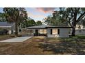Charming single-story home with white facade, dark trim, and a welcoming screened-in porch at sunset at 1650 W Mcleod St, Bartow, FL 33830