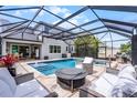 A covered pool and outdoor living space is furnished with a fireplace, spa, grill, and comfortable seating at 1909 Donahue Dr, Ocoee, FL 34761