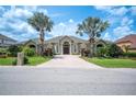 Beautiful front exterior with palm trees, well-manicured lawn, and a brick driveway at 715 Hanover Ct, Lakeland, FL 33813