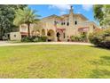 Charming Spanish style two-story home with a red tile roof, yellow stucco, an arched entry and lush landscaping at 845 E Edgewood Dr, Lakeland, FL 33803