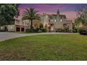 Elegant home boasts arched entryway, lush lawn, vibrant landscaping, and classic architectural details at sunset at 845 E Edgewood Dr, Lakeland, FL 33803