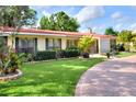 Well-maintained lawn and manicured landscaping surrounds this home with a red brick driveway and beautiful tropical features at 1407 Easton Dr, Lakeland, FL 33803
