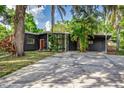 Charming single-story home with mature trees, modern gray siding, large windows, and an inviting red front door at 1604 Sylvester Rd, Lakeland, FL 33803