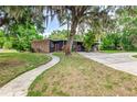 Picturesque home with mature trees, charming brick details, gray siding, and a welcoming walkway leading to the front door at 1604 Sylvester Rd, Lakeland, FL 33803