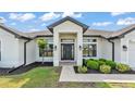 Inviting front entrance with a dark-colored door, modern lights, and freshly manicured landscaping at 185 Heritage Park Ln, Mulberry, FL 33860