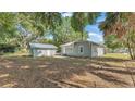 Exterior view of a single-story home with a detached garage and lush, mature trees surrounding the property at 2203 Avenue F Nw, Winter Haven, FL 33880