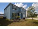 Side view of blue two-story home with landscaped front yard and two car garage on a sunny day at 3882 Resting Robin Ave, Bartow, FL 33830
