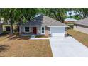 An eye-level view of a single-story home with a two car garage, manicured landscaping and fresh driveway at 6625 Thornhill Rd, Winter Haven, FL 33880