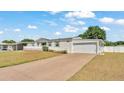 Home featuring an attached garage and a long drive, under a bright sky at 8341 Mitchall Dr, Lakeland, FL 33809