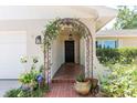 Inviting front porch with arched entry covered with flowering vines and brick steps at 1503 Clairdale Ln, Lakeland, FL 33801