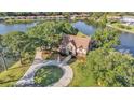 Charming Tudor-style home with stone accents, a circular driveway, and a manicured lawn near a serene lake at 3906 Canyon Lake Pt, Lakeland, FL 33813