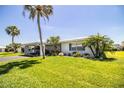 Single-story home showcasing lush green lawn, tropical landscaping, and a carport at 610 Cottage Ln, Lakeland, FL 33803