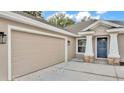 Close-up of a home featuring a wide two-car garage, a charming front door, and stylish exterior lighting at 803 Allison Place, Bartow, FL 33830