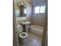 Full bathroom with tiled walls, a pedestal sink, toilet, and combined shower and bathtub at 1226 N Brunnell Pkwy, Lakeland, FL 33805