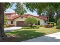 Beautiful home exterior with a well-manicured lawn, complemented by mature trees and a charming two-car garage at 139 Stratford Ct, Haines City, FL 33844