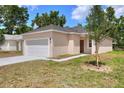 Cozy single-story home with a front lawn featuring a young tree and driveway leading to the garage at 1890 Martin Luther King, Jr. E Blvd, Bartow, FL 33830