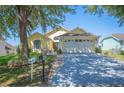 Well-maintained single-story home with a two-car garage, mature trees, and landscaped front yard at 217 Dillon Way, Davenport, FL 33897