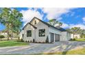 Side view showcasing the three-car garage and the home's stylish stone and neutral color palette at 5087 Cliffside Drive, Lakeland, FL 33813