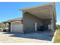 Side exterior showing garage, golf cart, and carport of home under a clear blue sky at 564 Meandering Way, Polk City, FL 33868