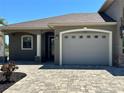 Exterior view of the home's garage and front entry, framed by manicured landscaping at 564 Meandering Way, Polk City, FL 33868
