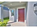 Inviting entryway showcases a stylish red front door with silver hardware and adjacent sidelight window at 752 Reggie Rd, Winter Haven, FL 33884