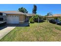 Charming ranch home with an attached garage, lush lawn, palms, an RV, and a car parked in the driveway at 7818 Lewis Rd, Lakeland, FL 33810