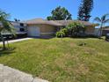 Charming ranch home with an attached garage, lush lawn, palms, and an RV parked in the driveway at 7818 Lewis Rd, Lakeland, FL 33810