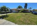 Charming ranch home with an attached garage, lush lawn, palms, an RV, and a car parked in the driveway at 7818 Lewis Rd, Lakeland, FL 33810