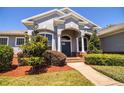 Inviting front porch with decorative columns and manicured bushes leading up to the home at 942 Hanover Way, Lakeland, FL 33813