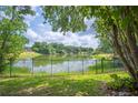 Scenic backyard view with a black metal fence overlooking a serene pond surrounded by lush greenery at 1104 Kells Ct, Lakeland, FL 33813
