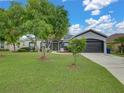 Well manicured lawn with mature tree highlights this home's charming exterior and convenient two-car garage at 2033 Normandy Heights Dr, Winter Haven, FL 33880