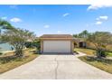 Beige one-story home with an attached two-car garage and a concrete driveway surrounded by a manicured lawn at 4428 Glenns Lndg, Winter Haven, FL 33884