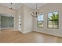 Bright living room with wood floors, modern lighting, and large windows showcasing lush landscaping at 5374 Clubhouse Hills Ln, Lakeland, FL 33812