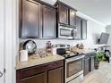 Kitchen featuring stainless steel appliances, dark cabinets, granite countertops, and tiled floors at 2112 Betsy Ross Ln, St Cloud, FL 34769