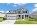 Daytime view of this two-story home's front featuring a large two-car garage, porch, and manicured lawn at 2468 Winnipeg Dr, Lakeland, FL 33805