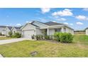 Lovely single-story home featuring a lush green lawn, two-car garage, and charming, well-maintained landscaping at 2611 San Marco Way, Winter Haven, FL 33884