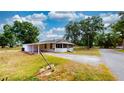 Exterior view of home showcasing a carport, screened porch, gravel driveway, and spacious front yard at 410 Orange St, Bradley, FL 33835