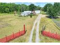 Wide shot of a property with a single Gathering home, storage sheds, and driveway framed by a red gate at 14810 Brahma Rd, Polk City, FL 33868