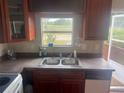 Kitchen featuring a double basin sink, cabinets, tile backsplash, and a view outside through the window at 14810 Brahma Rd, Polk City, FL 33868
