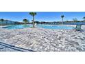 Large community swimming pool surrounded by palm trees and stylish pavers overlooking serene water at 1517 Leamington Ln, Winter Haven, FL 33884