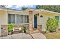 Close-up of a welcoming front porch with stone accents, a cozy bench, and a neatly landscaped entrance at 1965 Avenue F Sw, Winter Haven, FL 33880