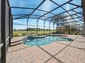 A luxurious screened pool with a brick deck and serene views beyond the enclosure for outdoor enjoyment at 4193 Stone Creek Loop, Lake Wales, FL 33859