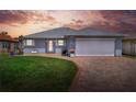 Charming single-story home with a brick driveway, lush lawn, and manicured landscaping at sunset at 525 Eagle Run, Lakeland, FL 33809
