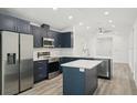 Modern kitchen boasts navy cabinetry, stainless steel appliances, center island and laminate flooring at 950 W 2Nd St, Lakeland, FL 33805