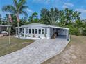 Charming home featuring a paver driveway, carport, and landscaped front yard with a palm tree at 1642 Tally Ho Dr, Lakeland, FL 33810