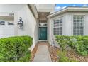 Inviting front entrance with a green door, decorative sidelight window, and lush shrubbery at 3592 Prescott Loop, Lakeland, FL 33810