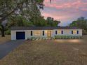 Charming single-story home with fresh exterior paint, shutters, a new roof and a paved driveway at dusk at 3705 Garland St, Mulberry, FL 33860